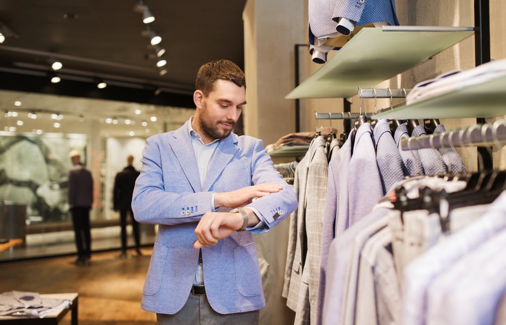 Happy Young Man Trying Jacket on in Clothing Store